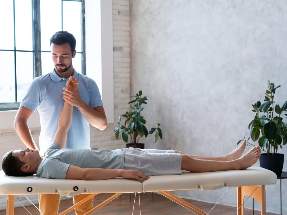 A physical therapist performing a hands-on leg stretch with a patient