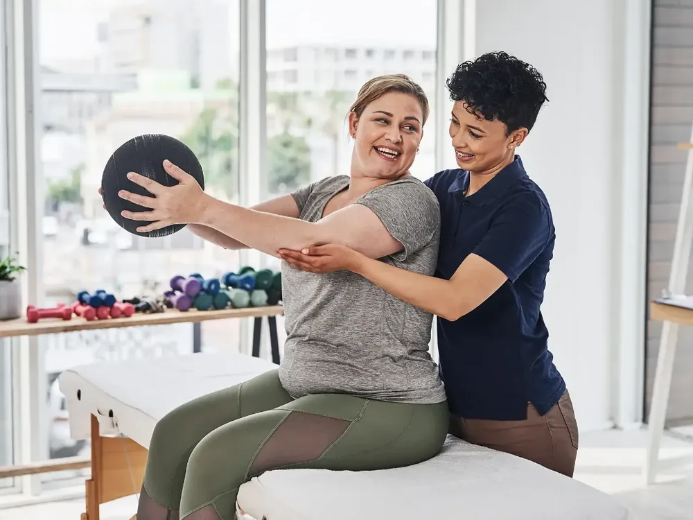 A physical therapist guiding a patient through a hands-on shoulder exercise